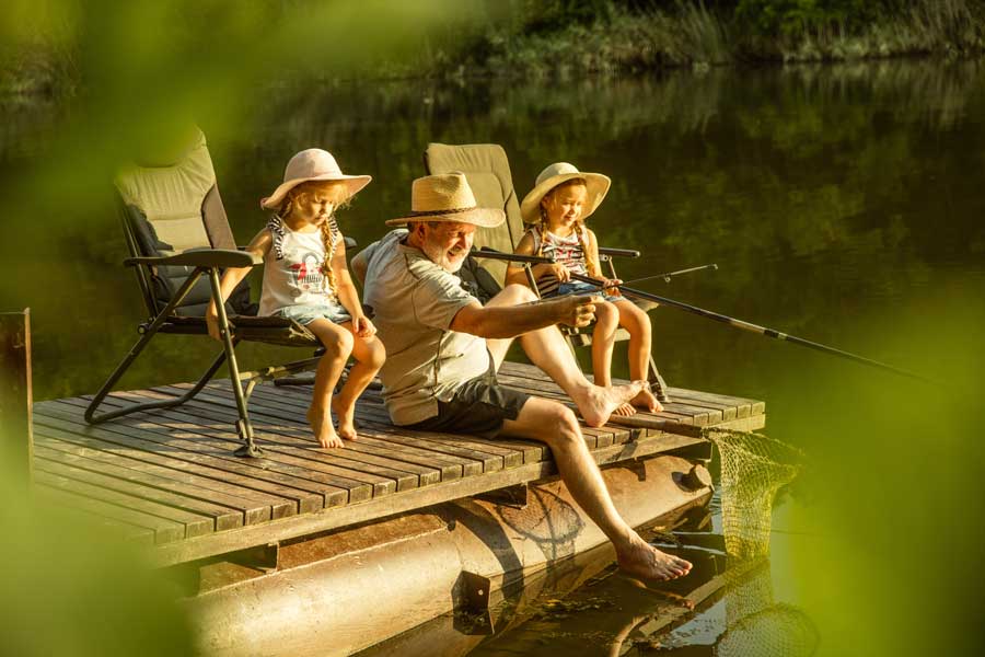 grandfather-granddaughters-fishing Gandfather sitting on dock with grandaughters fishing