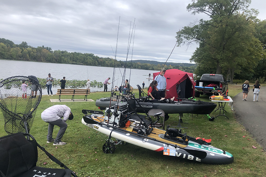 Several fishing boats on trailers on a shoreline with fishermen scattered around preparing tackle and gear.