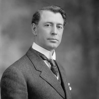 A black and white photograph of Key Pittman wearing a fine suit and posing for the camera.